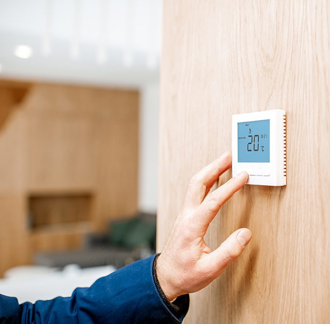 Adjusting temperature with thermostat at home Adjusting room temperature with electronic thermostat at home, close-up view with no face